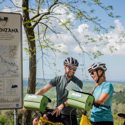 Two cyclists looking at a map at Parenzana trail with scenic landscape