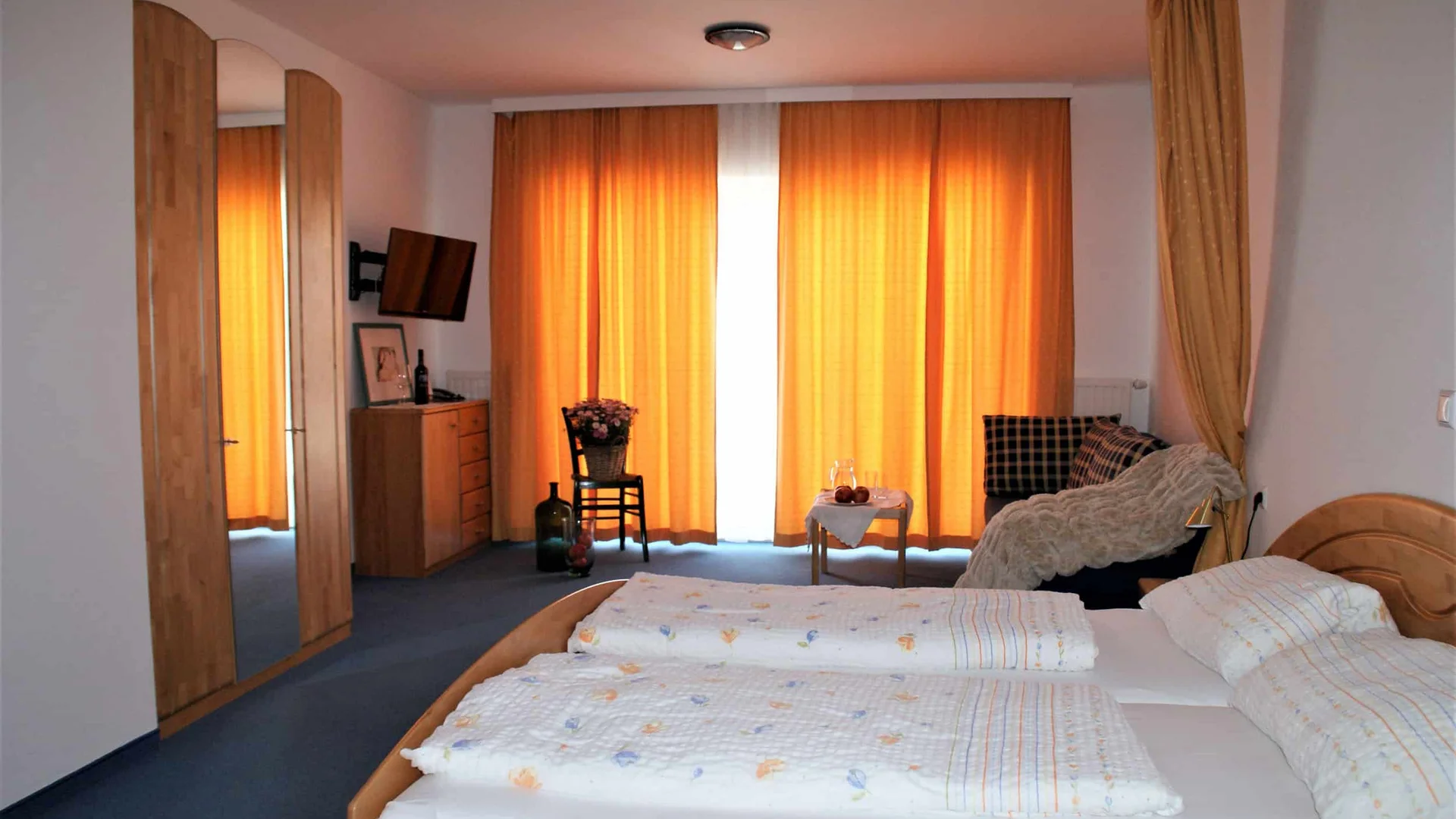 Gezellige slaapkamer met tweepersoonsbed en oranje gordijnen
