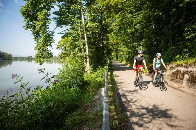Zwei Radfahrer auf einem Weg neben einem Fluss im Wald