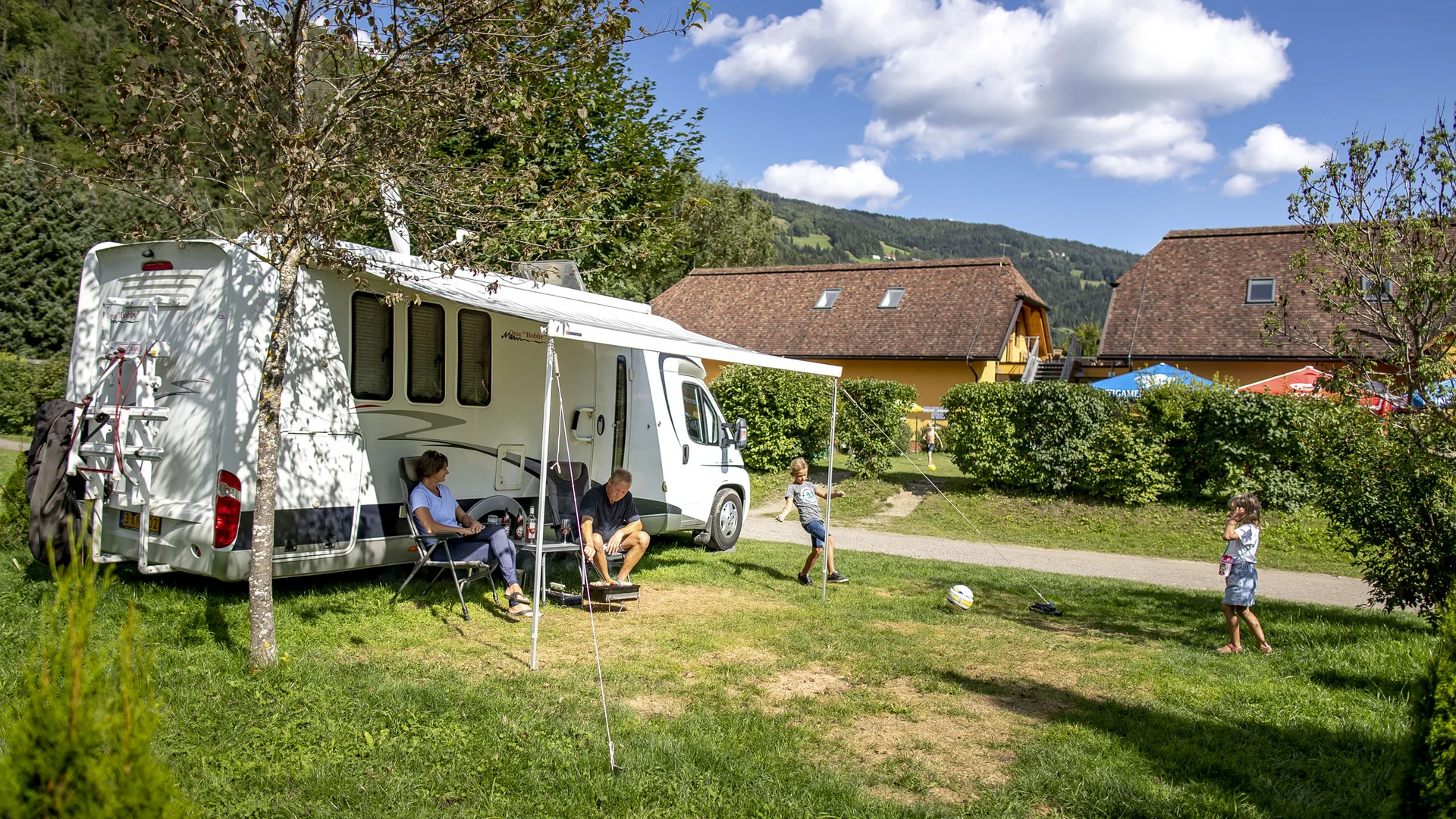 Gezin met kinderen speelt naast een camper op een camping