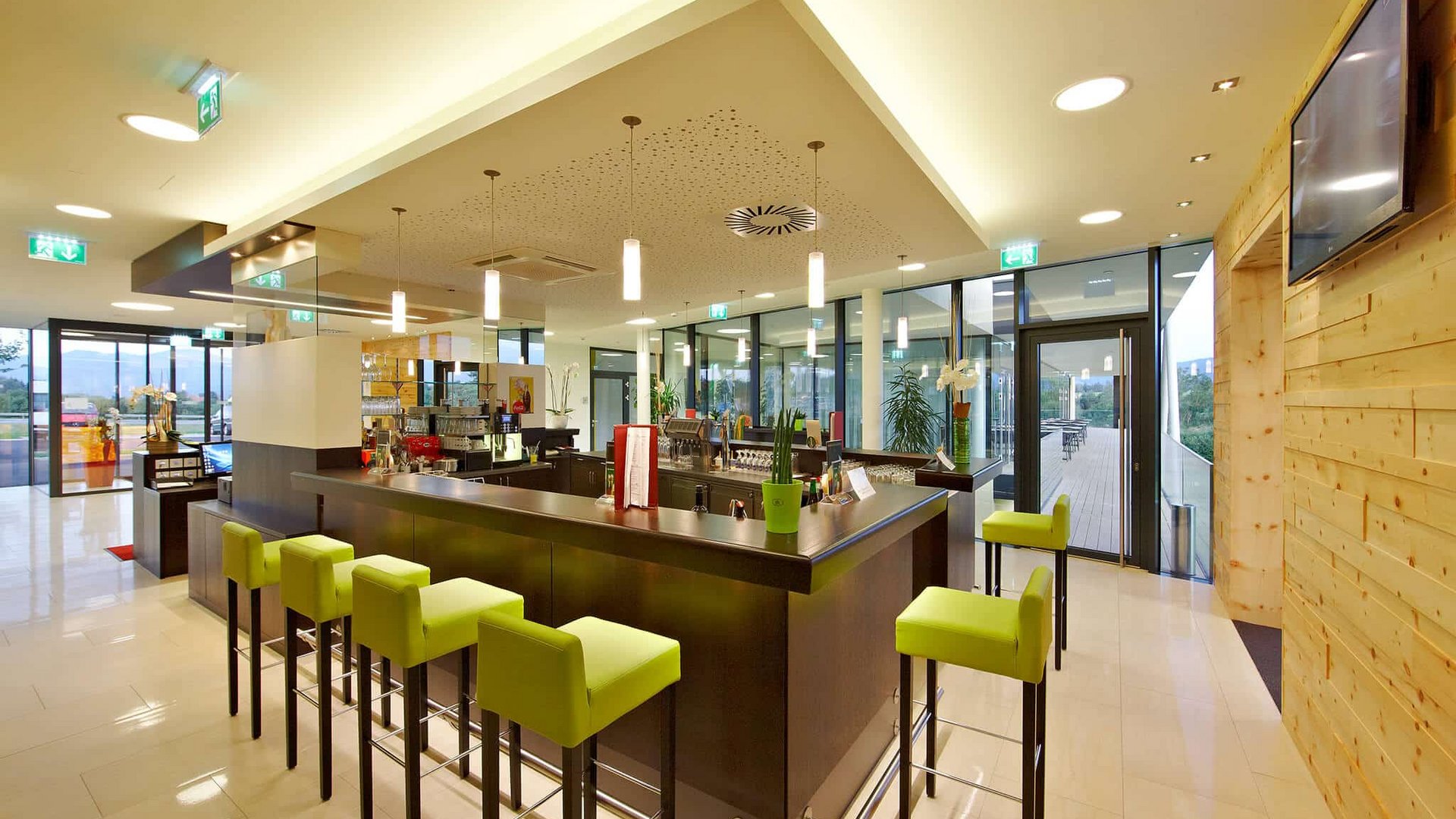 Modern bar area with green bar stools and large glass windows