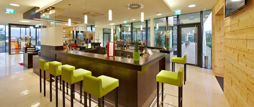 Modern bar area with green bar stools and large glass windows