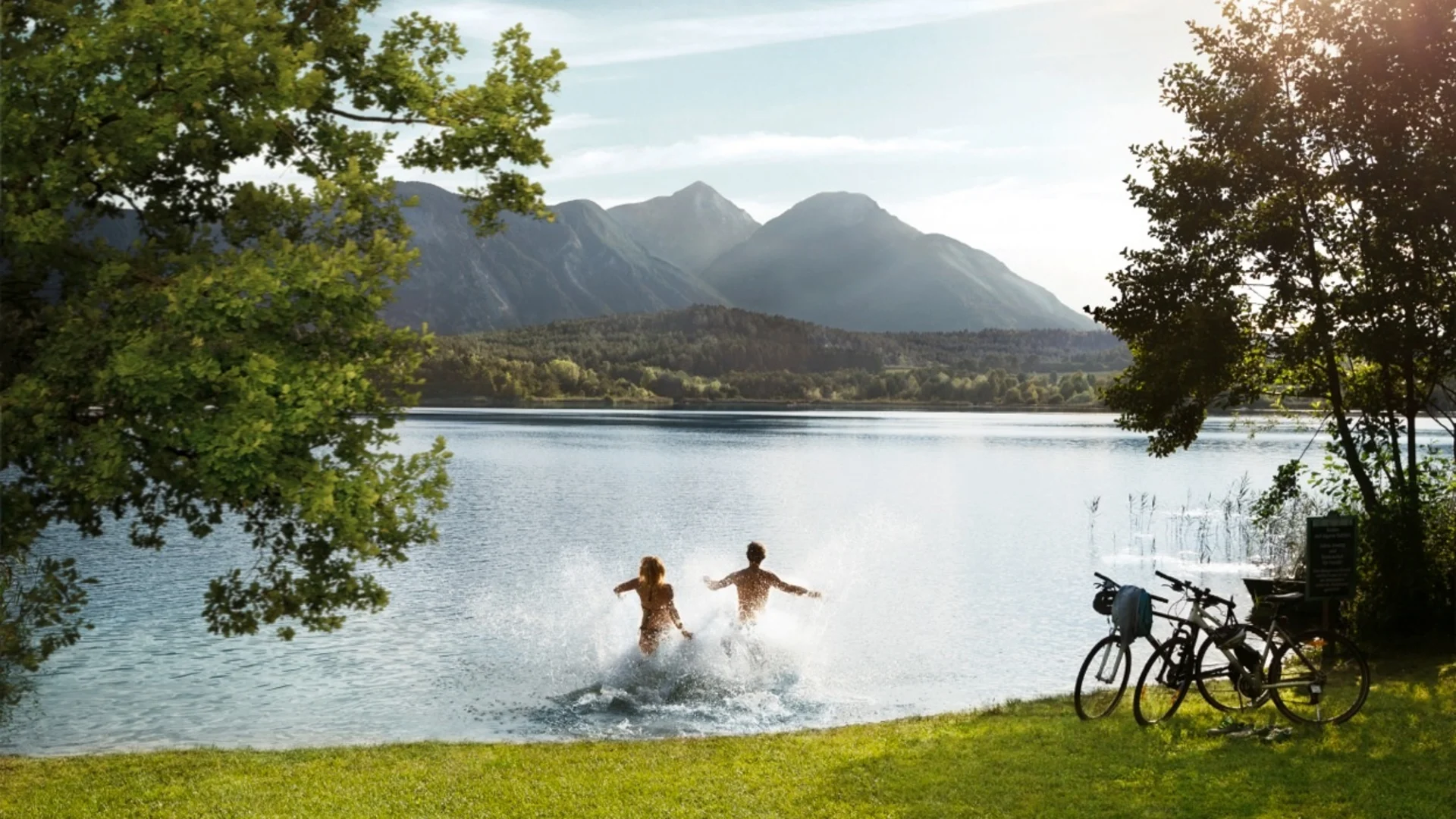 Twee mensen springen in een meer met bergen op de achtergrond