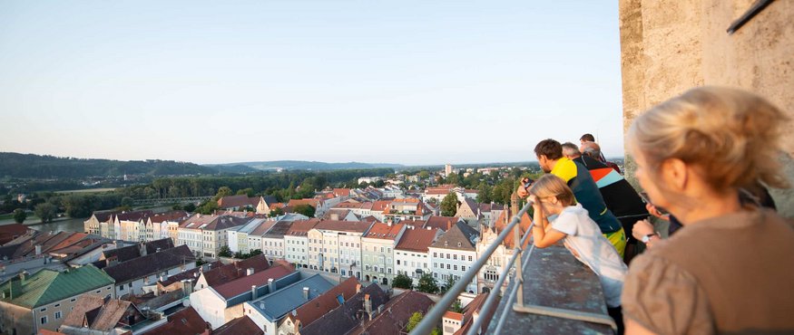 People enjoying view from balcony over town and hills under clear sky