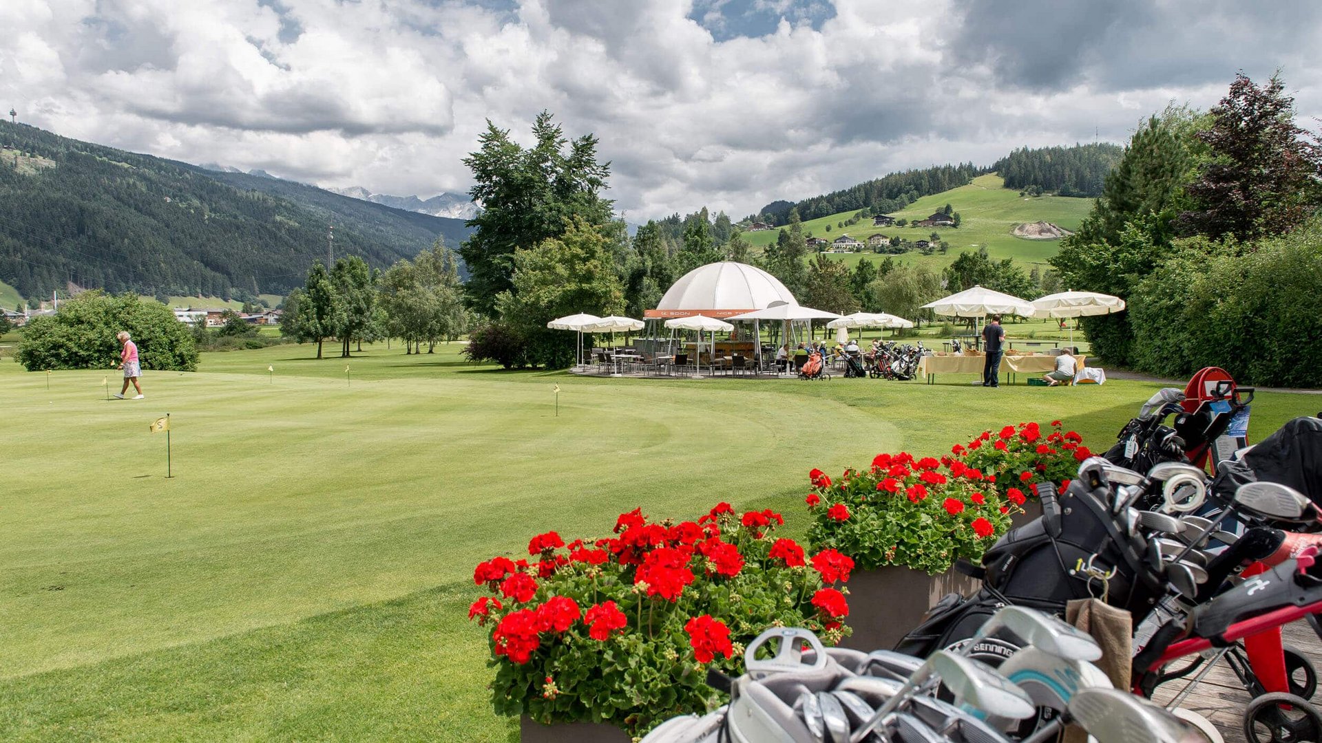 Golf course with red flowers and mountains in the background