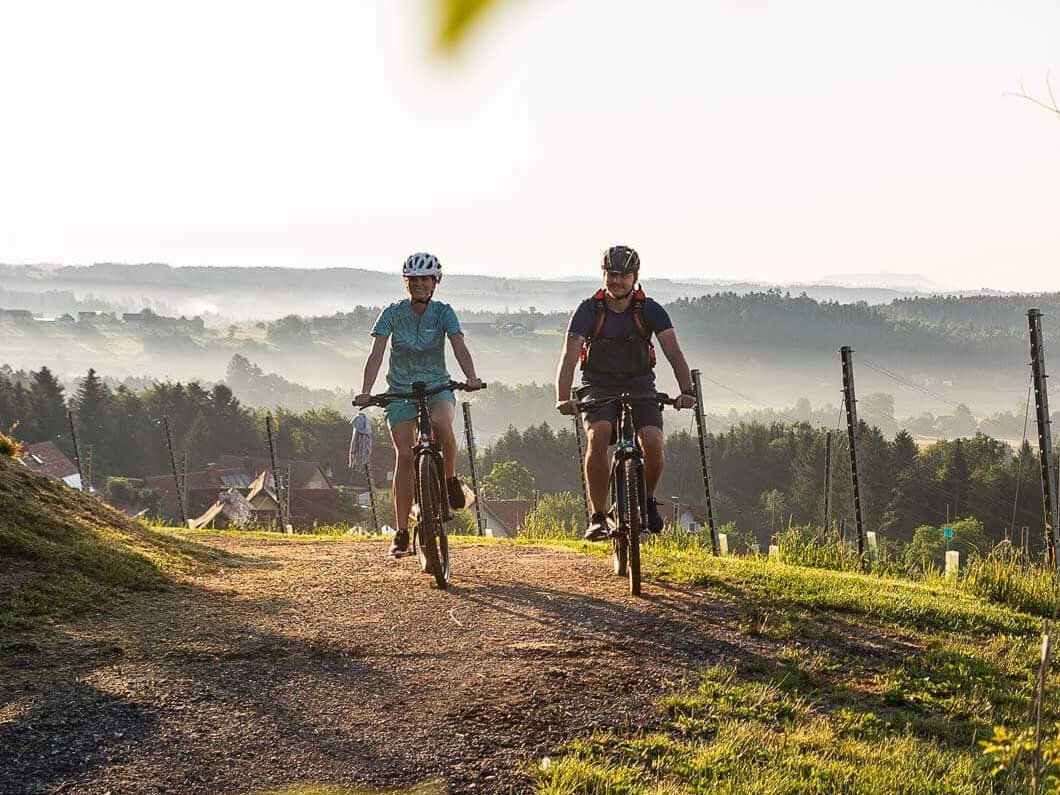 Zwei Radfahrer fahren auf einem Weg durch eine Landschaft bei Sonnenaufgang
