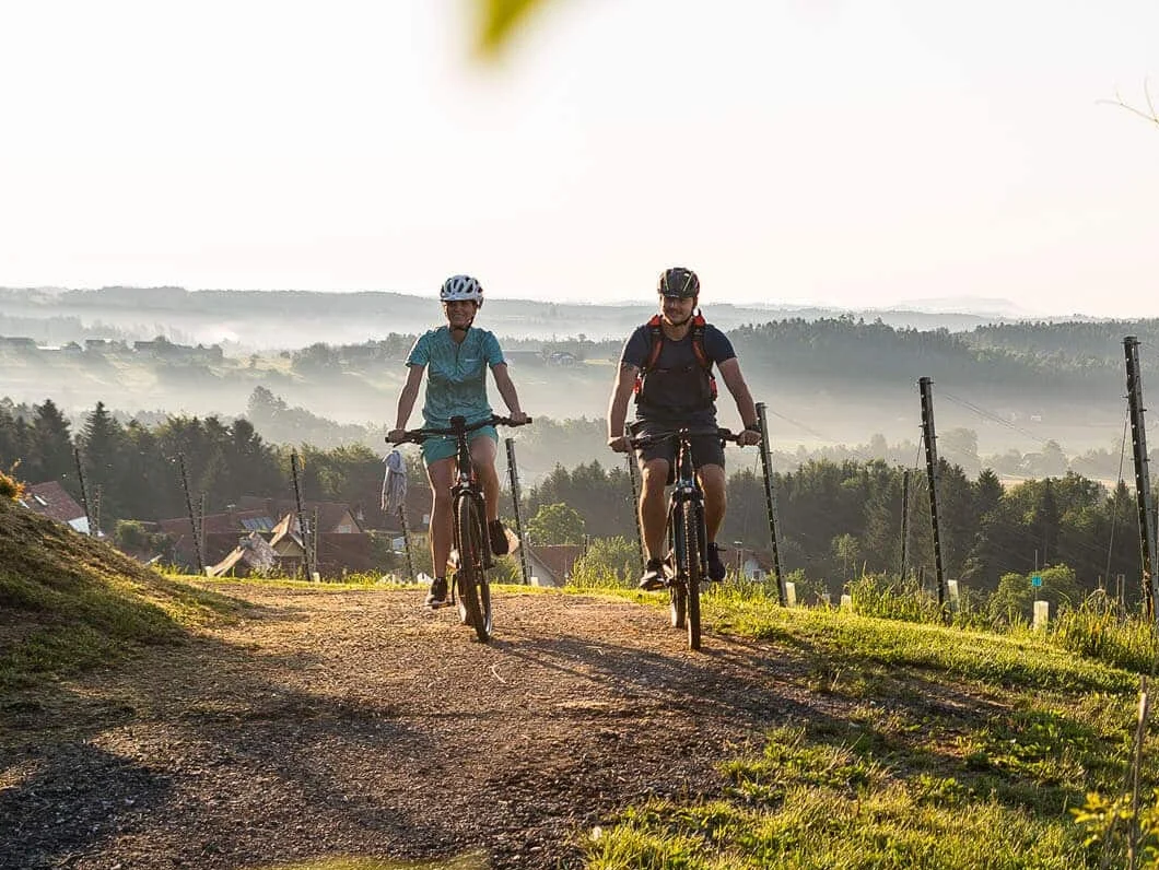 Zwei Radfahrer fahren auf einem Weg durch eine Landschaft bei Sonnenaufgang