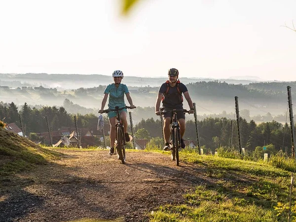 Zwei Radfahrer fahren auf einem Weg durch eine Landschaft bei Sonnenaufgang