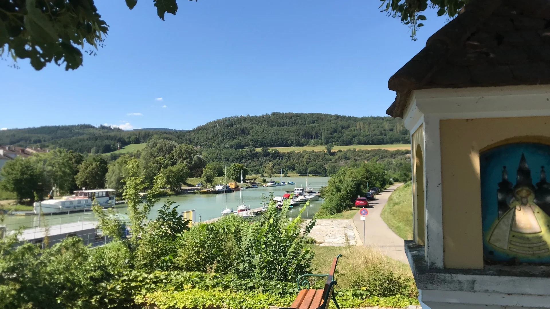 Erlauftalradweg Blick auf Fluss mit Booten, Hügel und Bank unter Bäumen an Kapelle