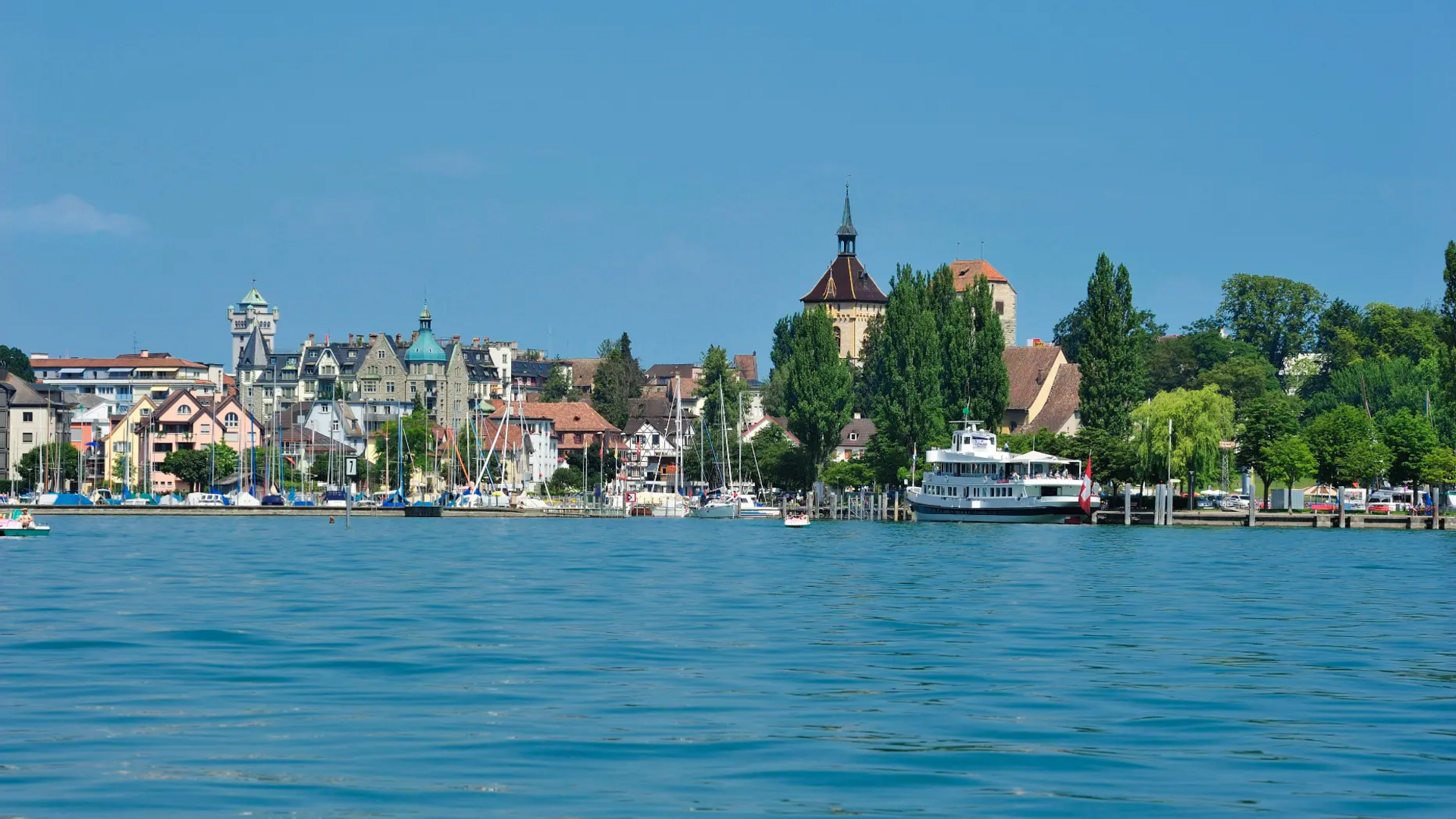 View of harbor town with boats and historic buildings under clear sky