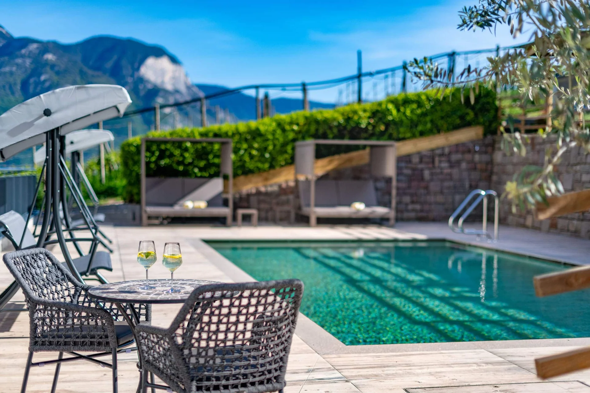 Pool mit Sitzbereich und zwei Gläsern auf dem Tisch bei sonnigem Wetter