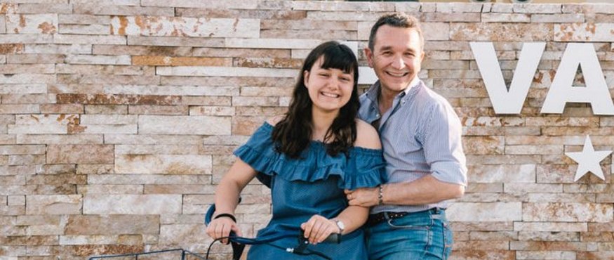 Smiling couple posing with bicycle in front of modern building