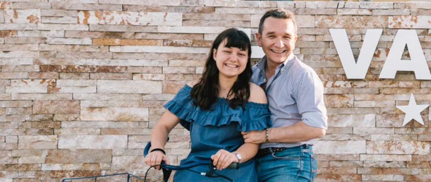 Smiling couple posing with bicycle in front of modern building
