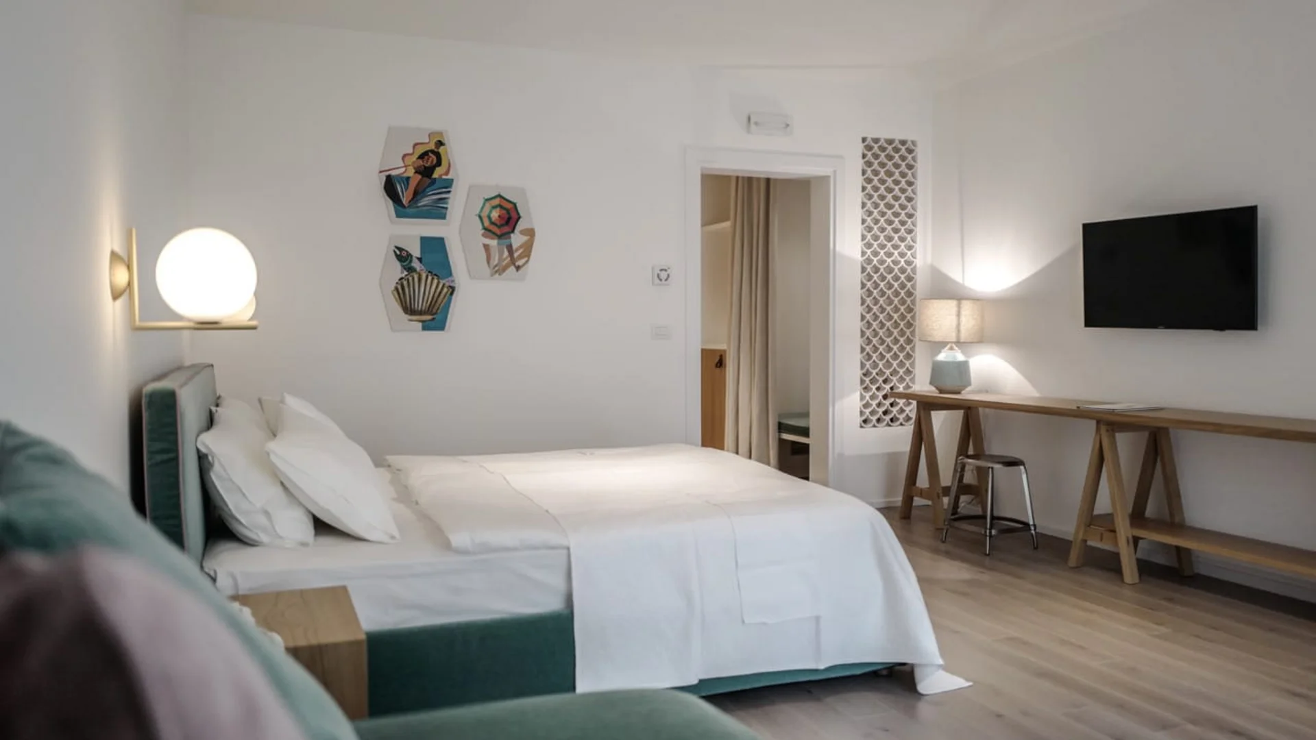 Modern bedroom with white bedding, wall art, and flat screen TV