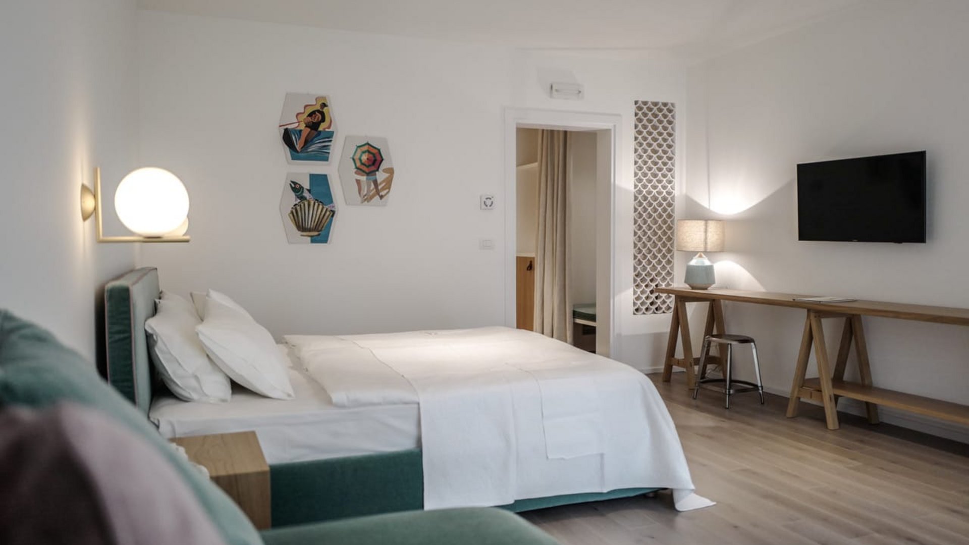 Modern bedroom with white bedding, wall art, and flat screen TV
