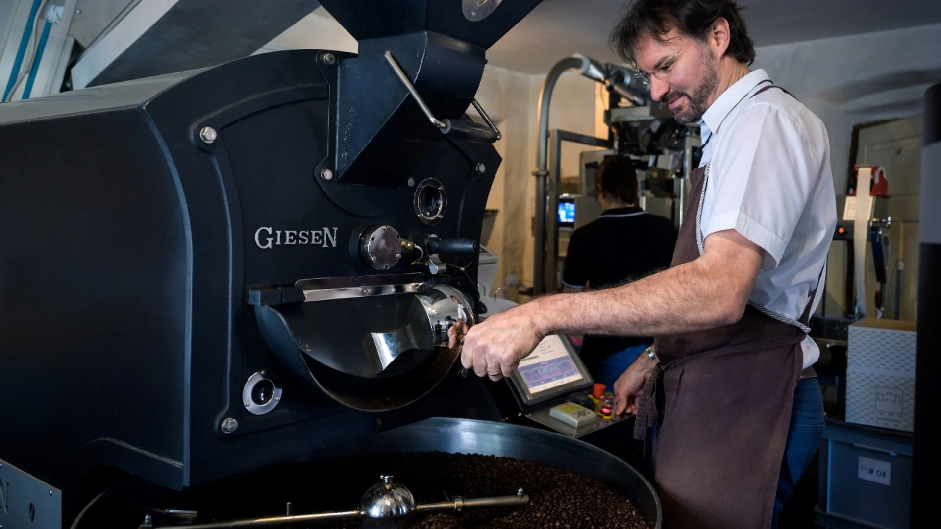 Mann bedient Kaffeemaschine zum Rösten von Kaffeebohnen