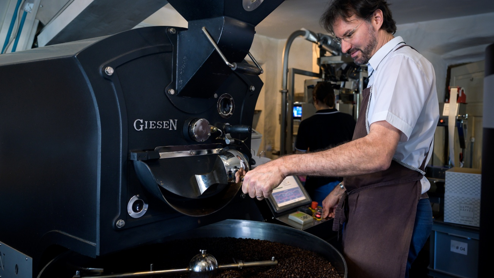 Man operating coffee roaster machine with roasted coffee beans