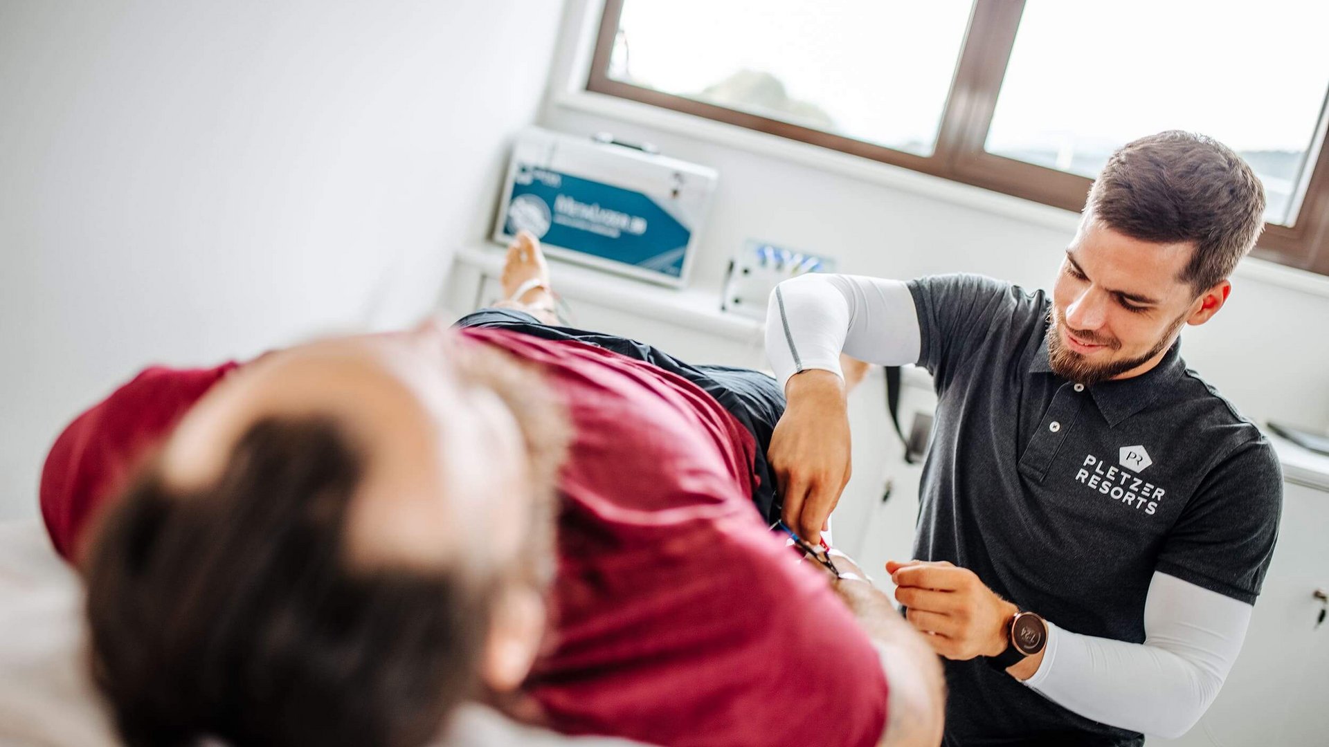Physiotherapist treating patient arm in bright therapy room