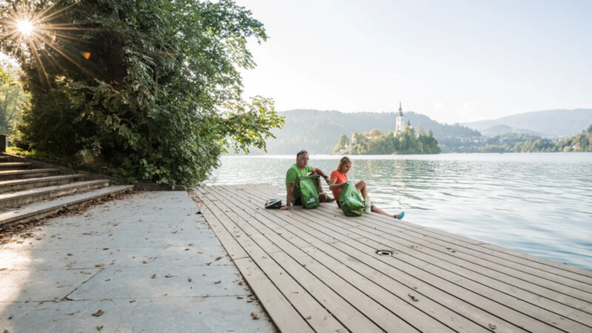 Dolomites - Trieste © FunActive Tours Two people sitting on a dock overlooking an island with a church