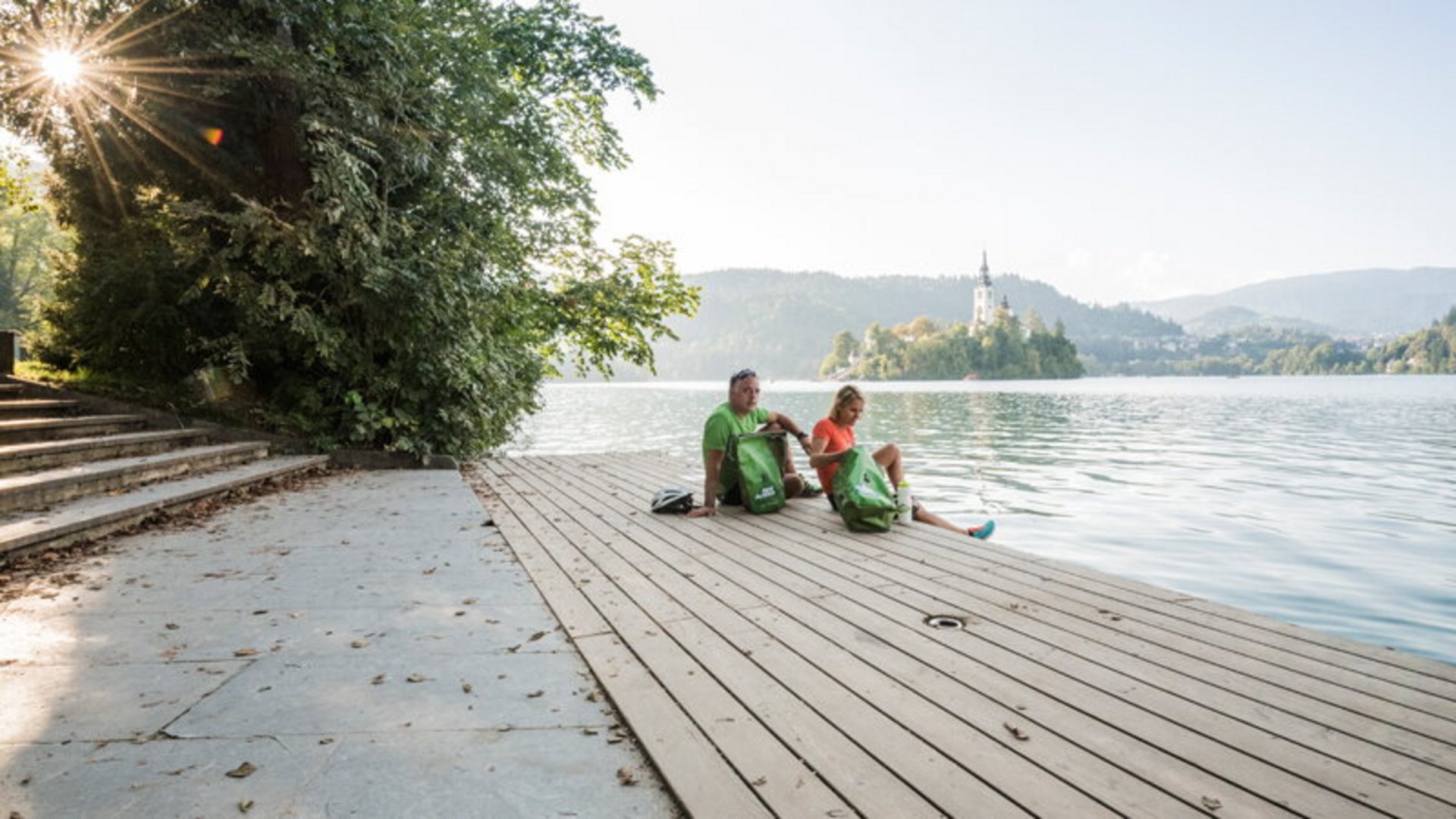 Two people sitting on a dock overlooking an island with a church
