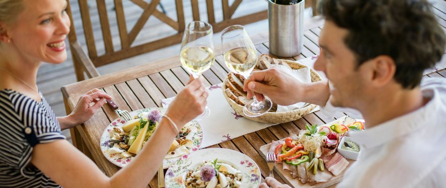 Couple toasting with white wine glasses during outdoor meal