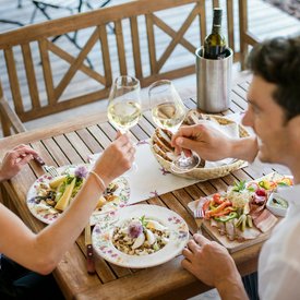 Couple toasting with white wine glasses during outdoor meal