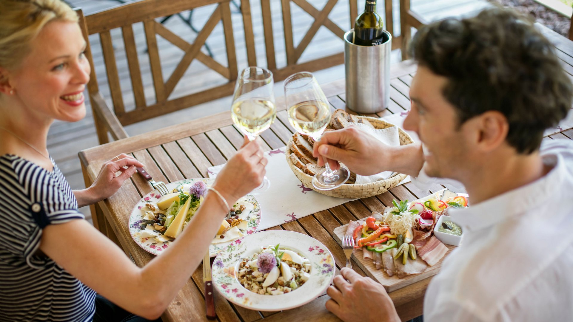 Couple toasting with white wine glasses during outdoor meal
