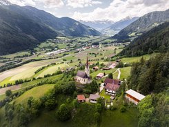 Village and church in green valley between mountains with snow-capped peaks