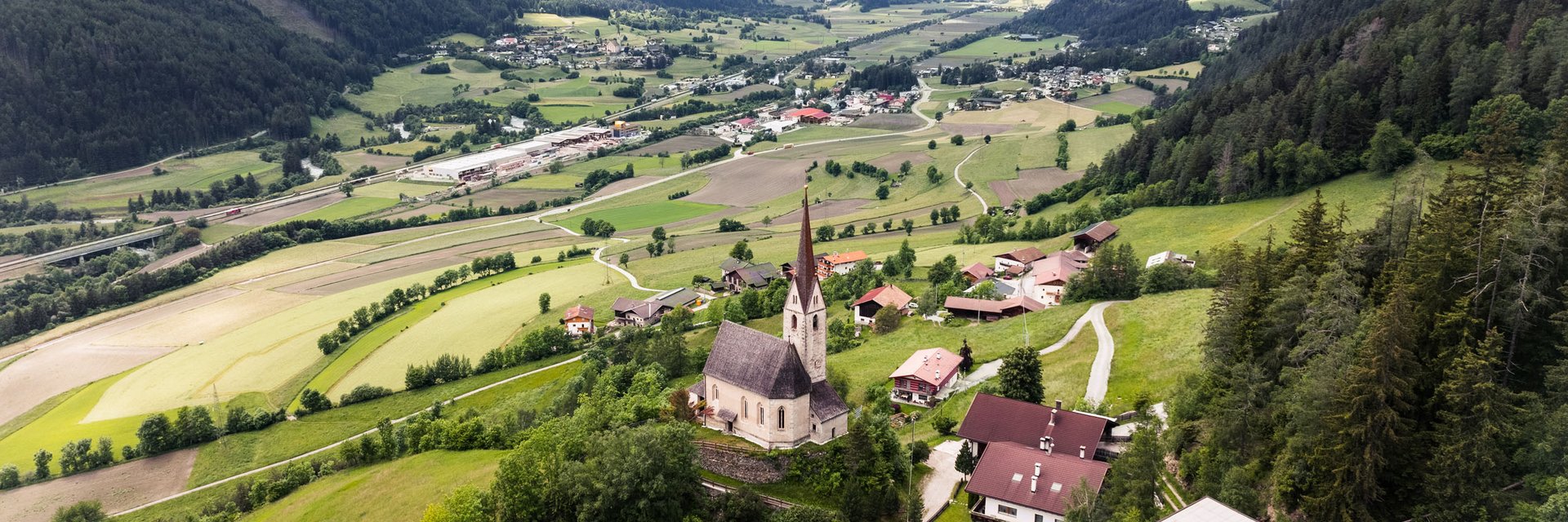 Village and church in green valley between mountains with snow-capped peaks