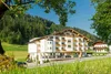 Collective enquiries Hotel building in green landscape with trees and mountains in the background