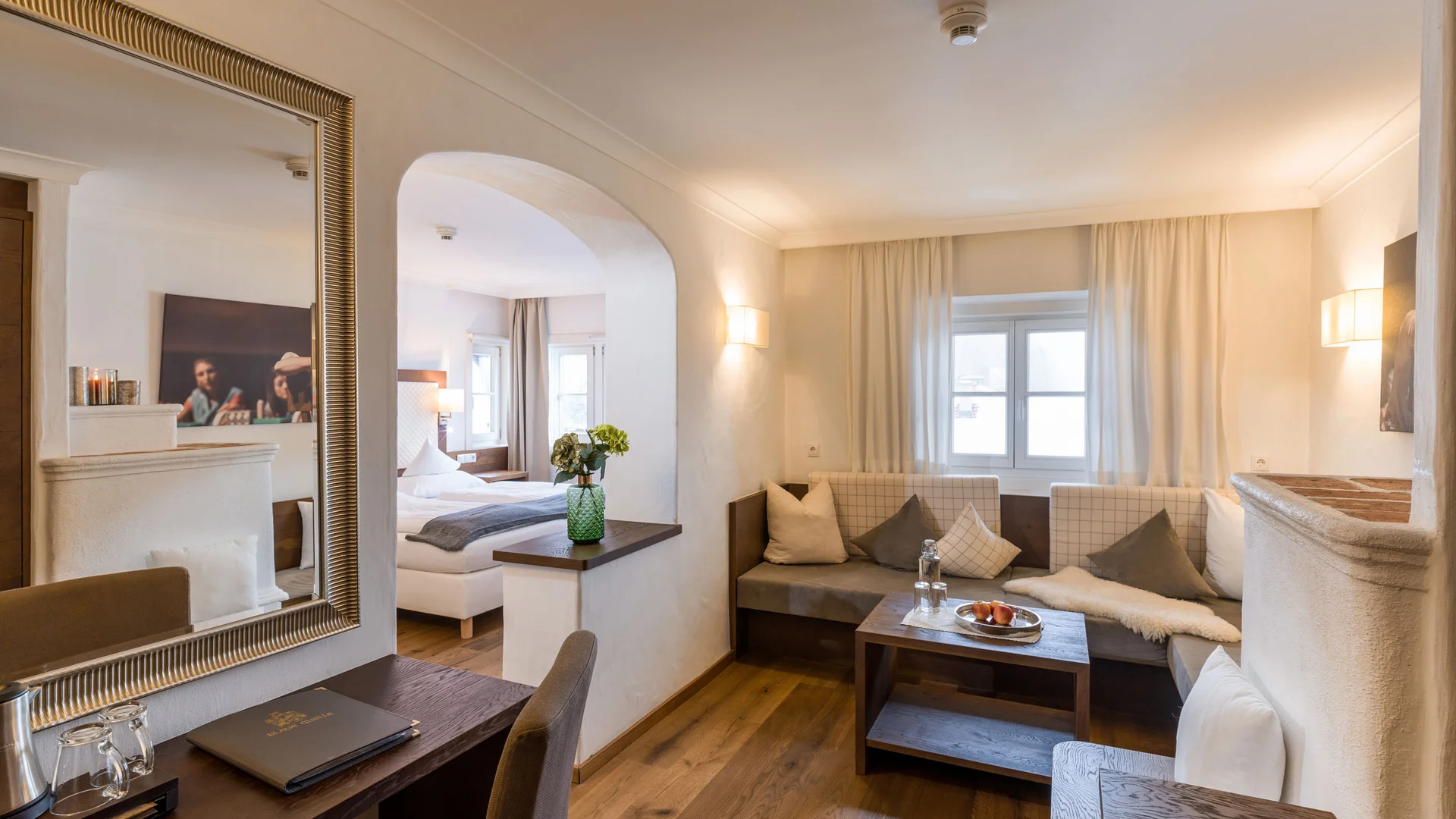 Cozy hotel room with seating area, desk, and a view into the bedroom