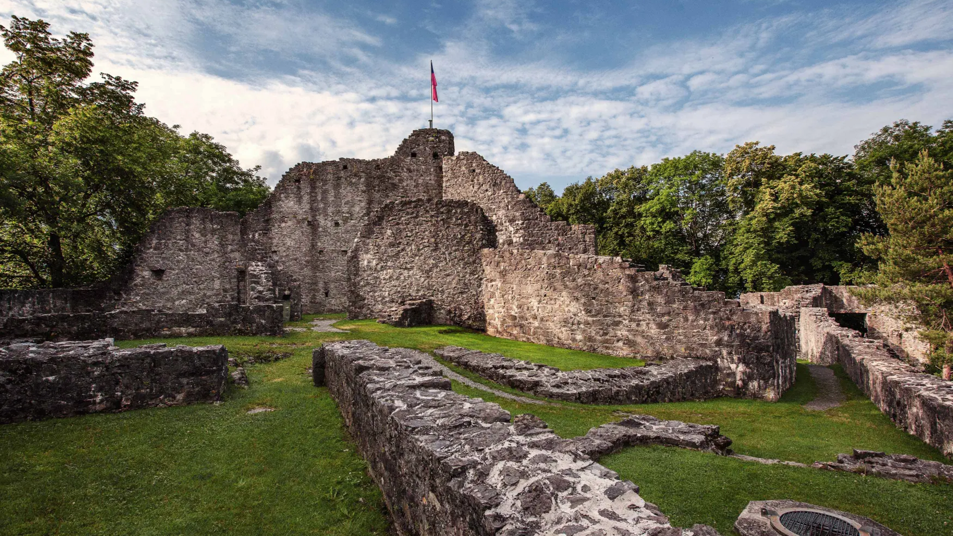 Ruins of an old castle with a flag and grassy courtyard