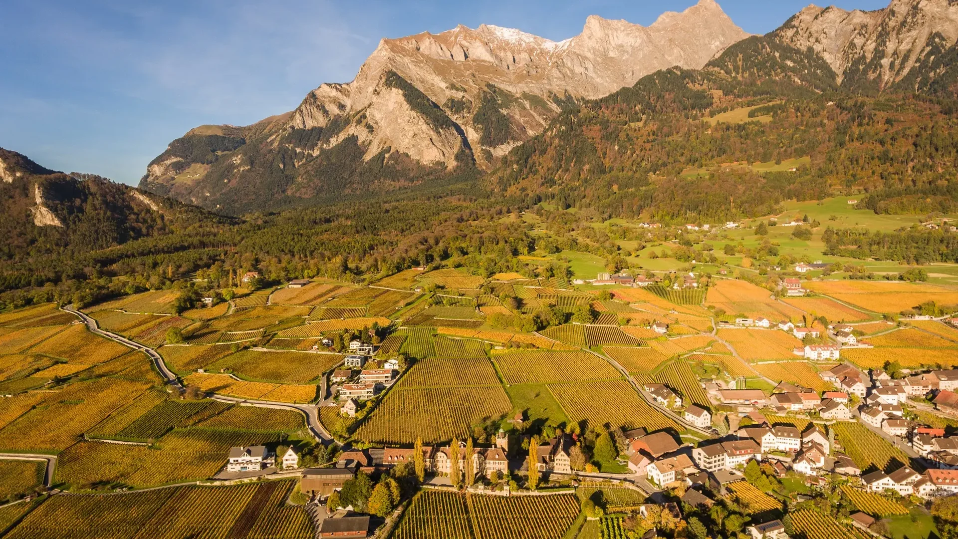Berglandschaft mit Weinbergen und Dorf im Sonnenlicht