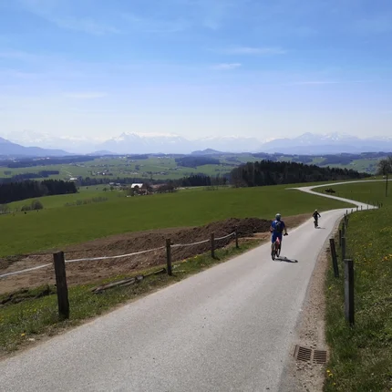 Twee fietsers op een landweg met bergen op de achtergrond