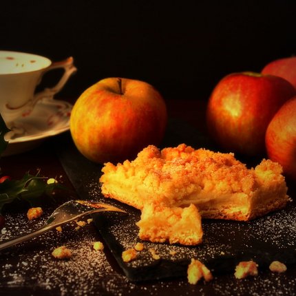 Apple cake with apples, coffee cup and decoration on dark surface