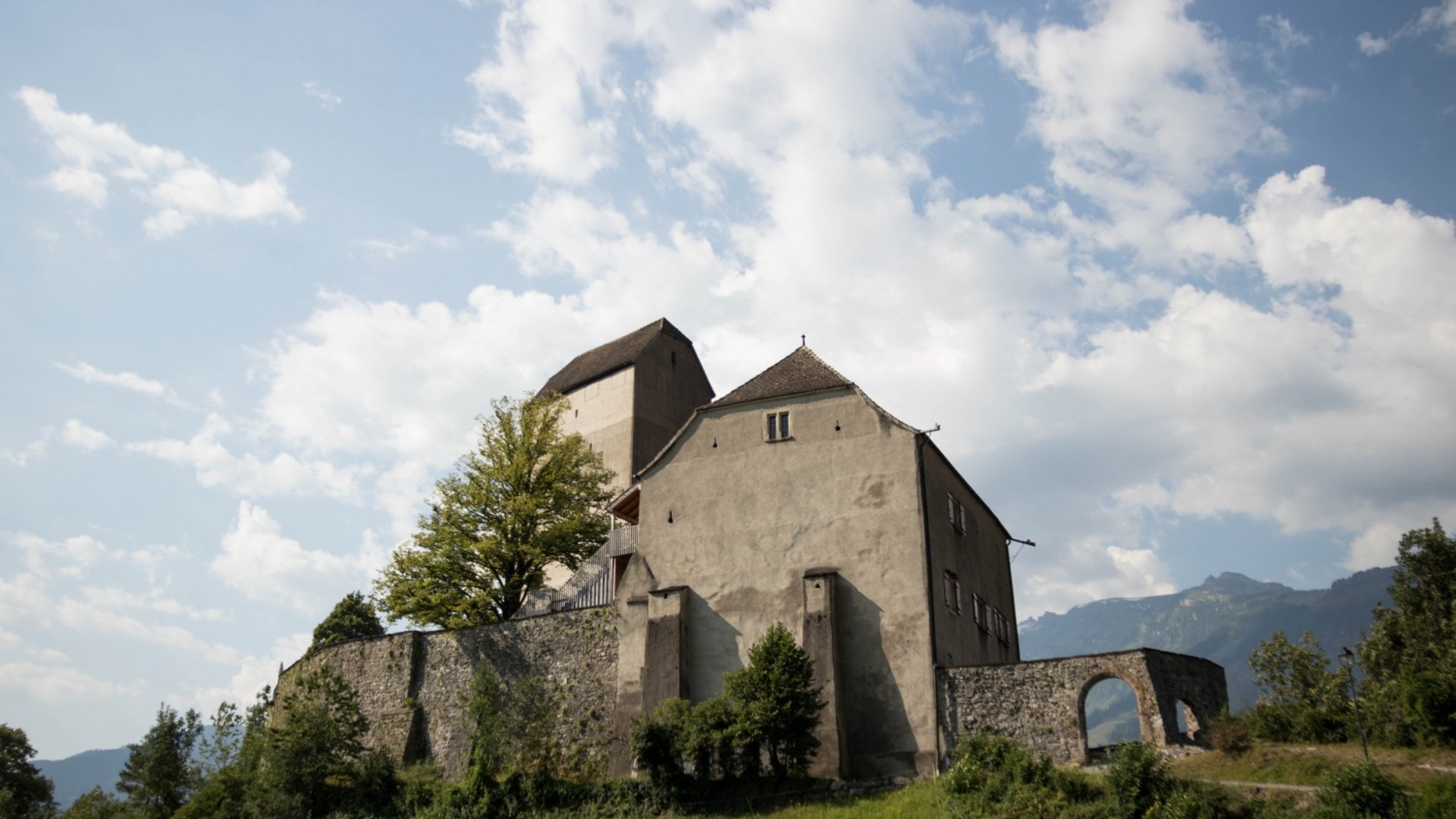 Old castle on green hill under cloudy sky