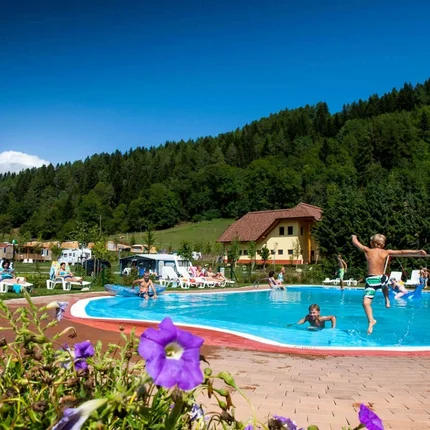 Kinder springen in einen Pool auf einem Campingplatz in den Bergen