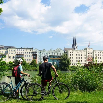 Twee fietsers met helmen kijken naar historische gebouwen aan de rivier