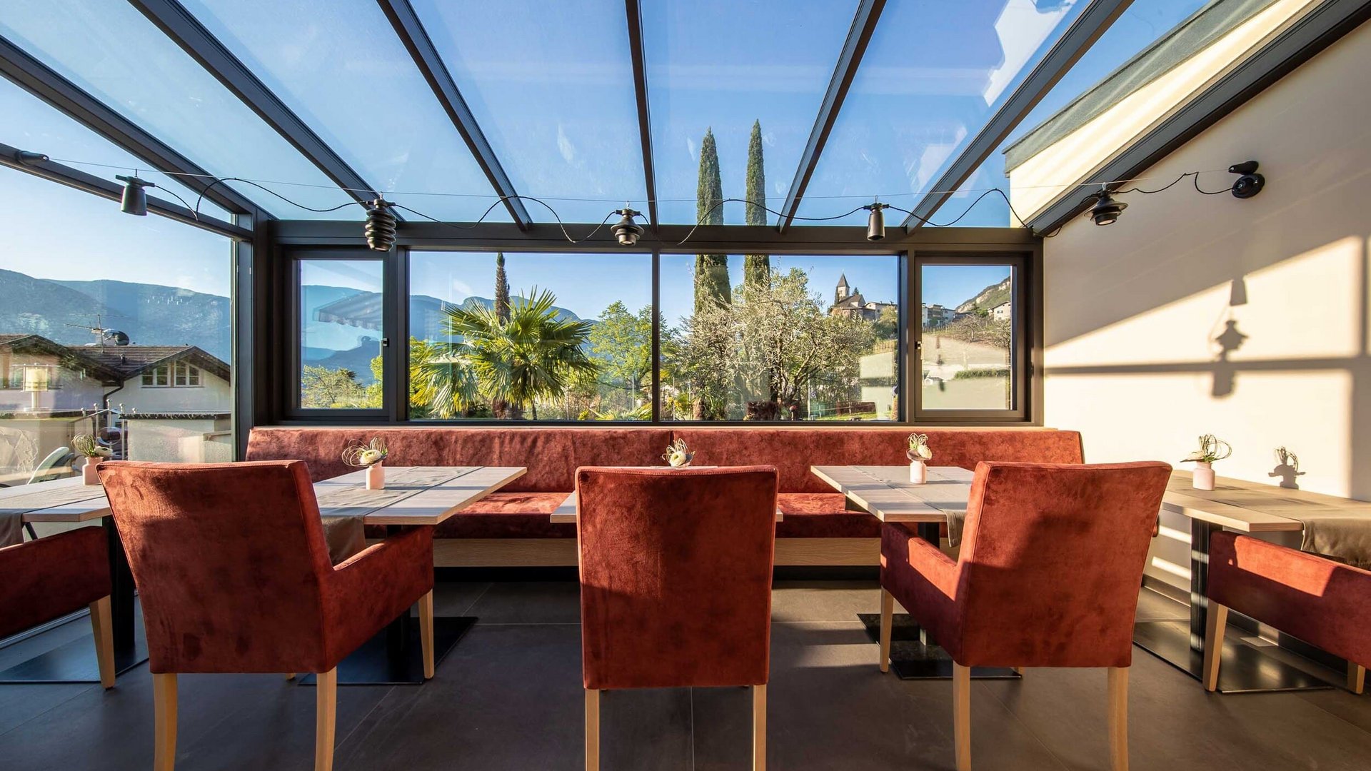 Modern terrace with glass roof and red seating overlooking mountains