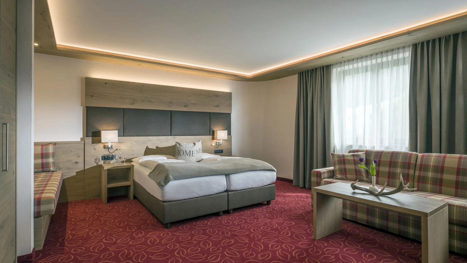 Hotel Andreas Hofer Kufstein **** © Hotel Andreas Hofer Kufstein Modernes Hotelzimmer mit Doppelbett, Sofa und rotem Teppich