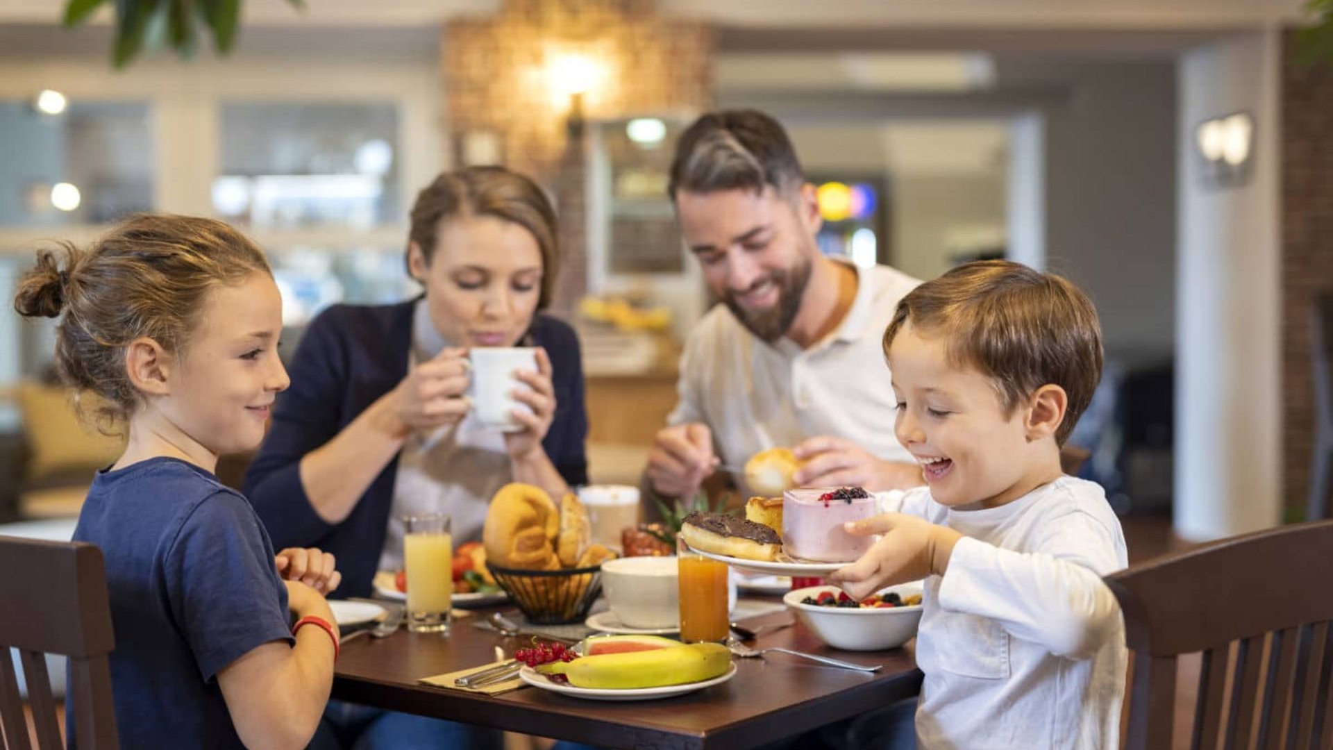 Family enjoying breakfast with fruits and pastries at the dining table