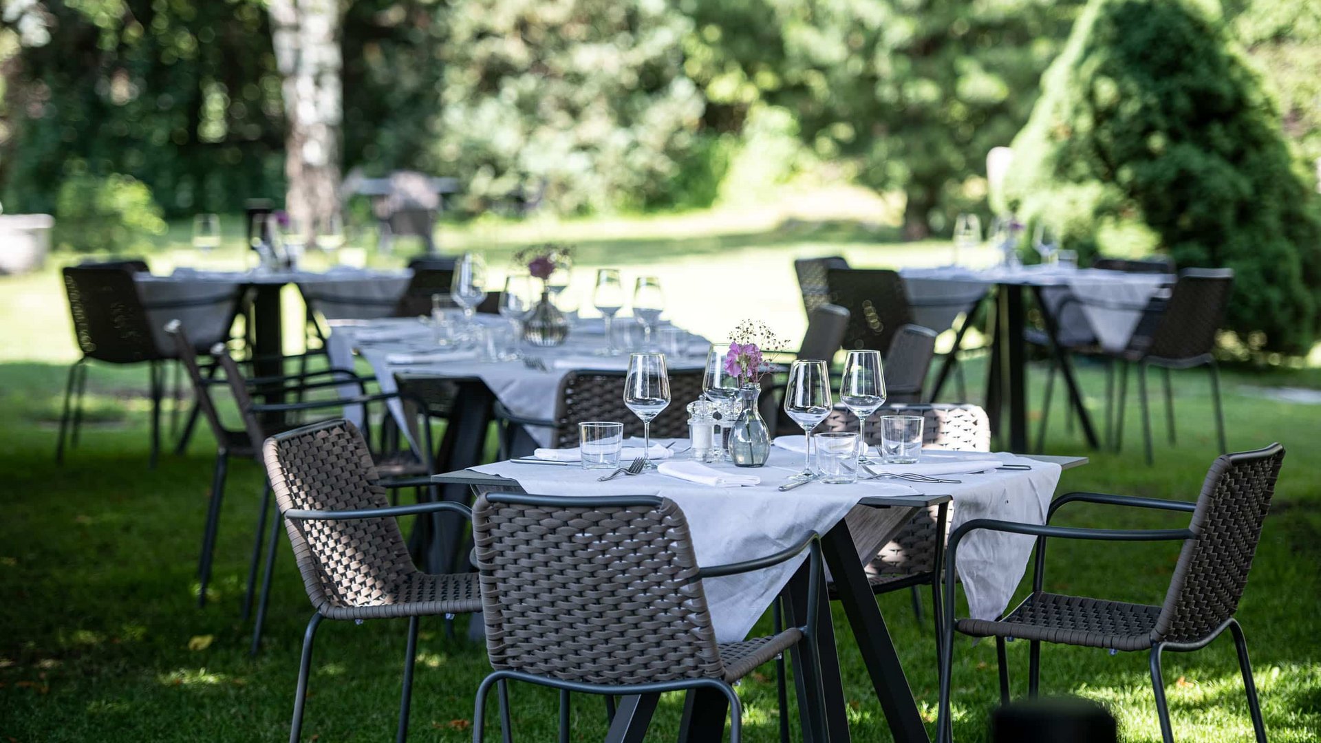 Outdoor garden tables set with white tablecloths and glasses for event
