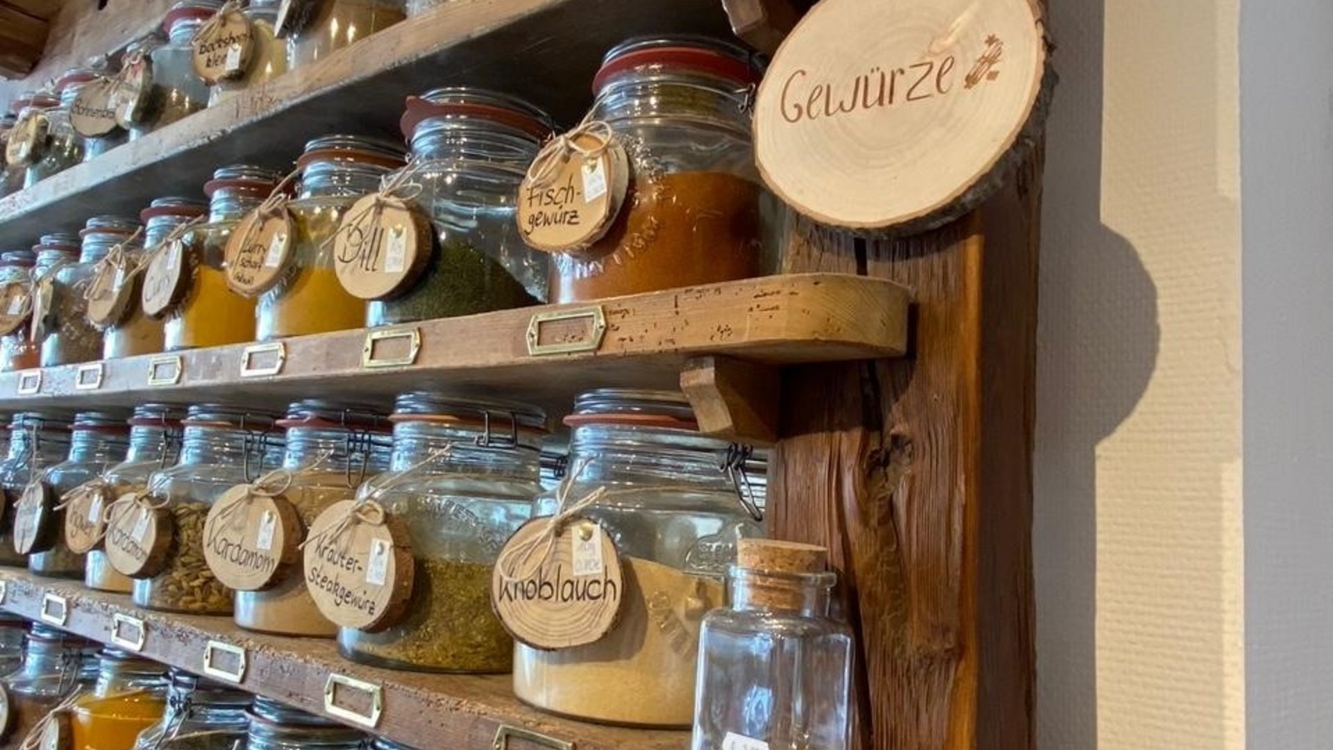 Spices in labeled glass jars on wooden shelves