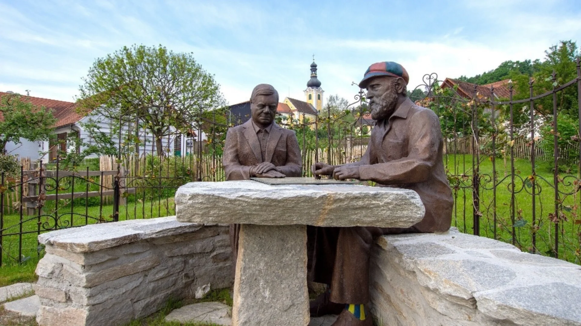 Steen beeld van twee mannen die buiten aan een stenen tafel spelen