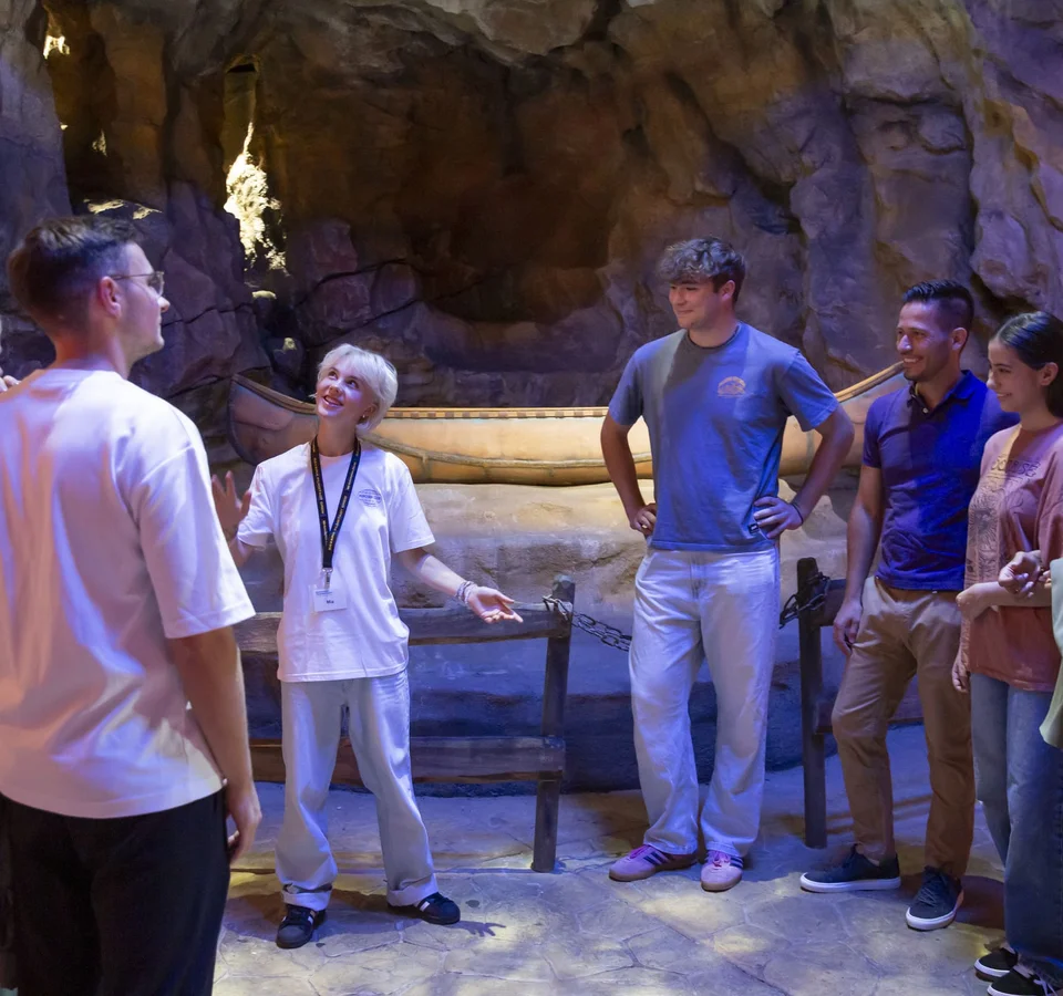 Filmreife Radelpause © Bavaria Filmstadt Eine Gruppe hört einem Guide in einer beleuchteten Höhle zu