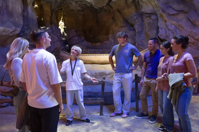 Eine Gruppe hört einem Guide in einer beleuchteten Höhle zu