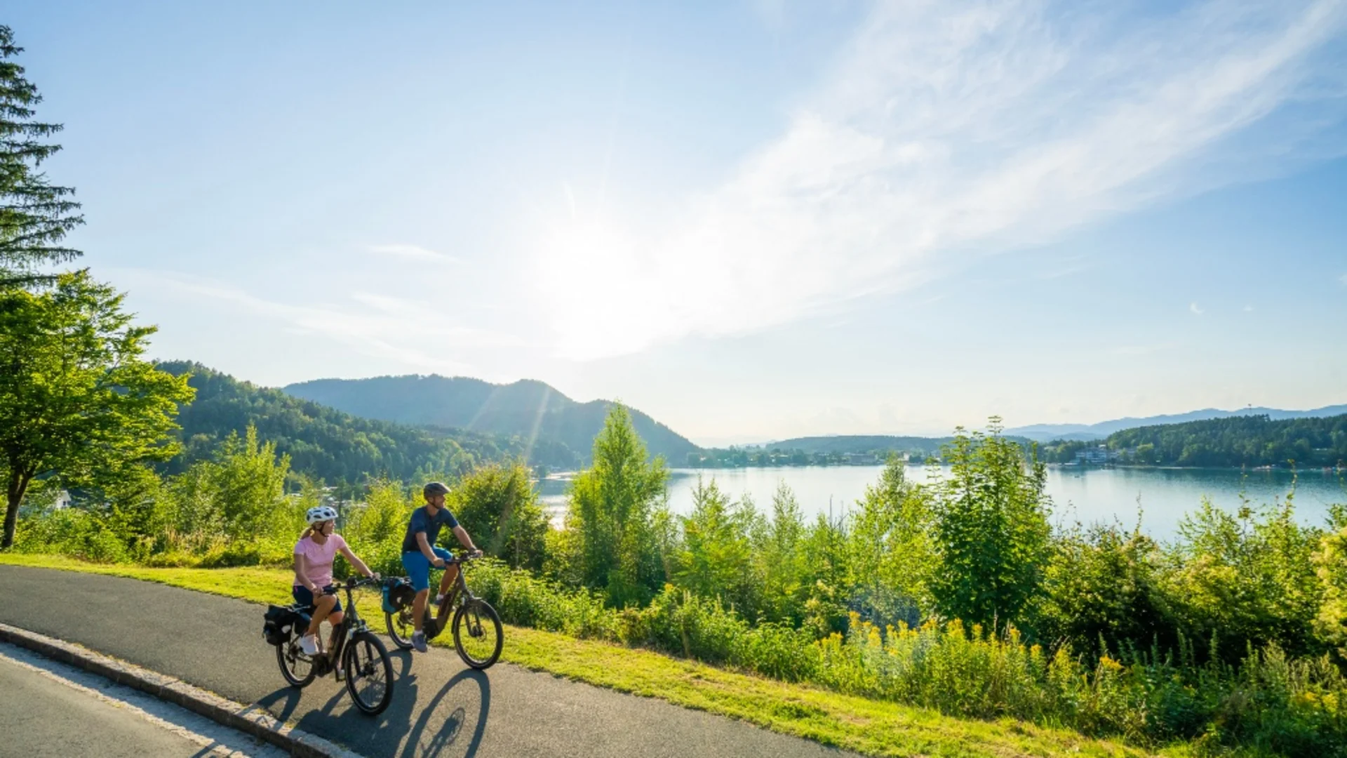Twee fietsers op een pad naast een meer op een zonnige dag