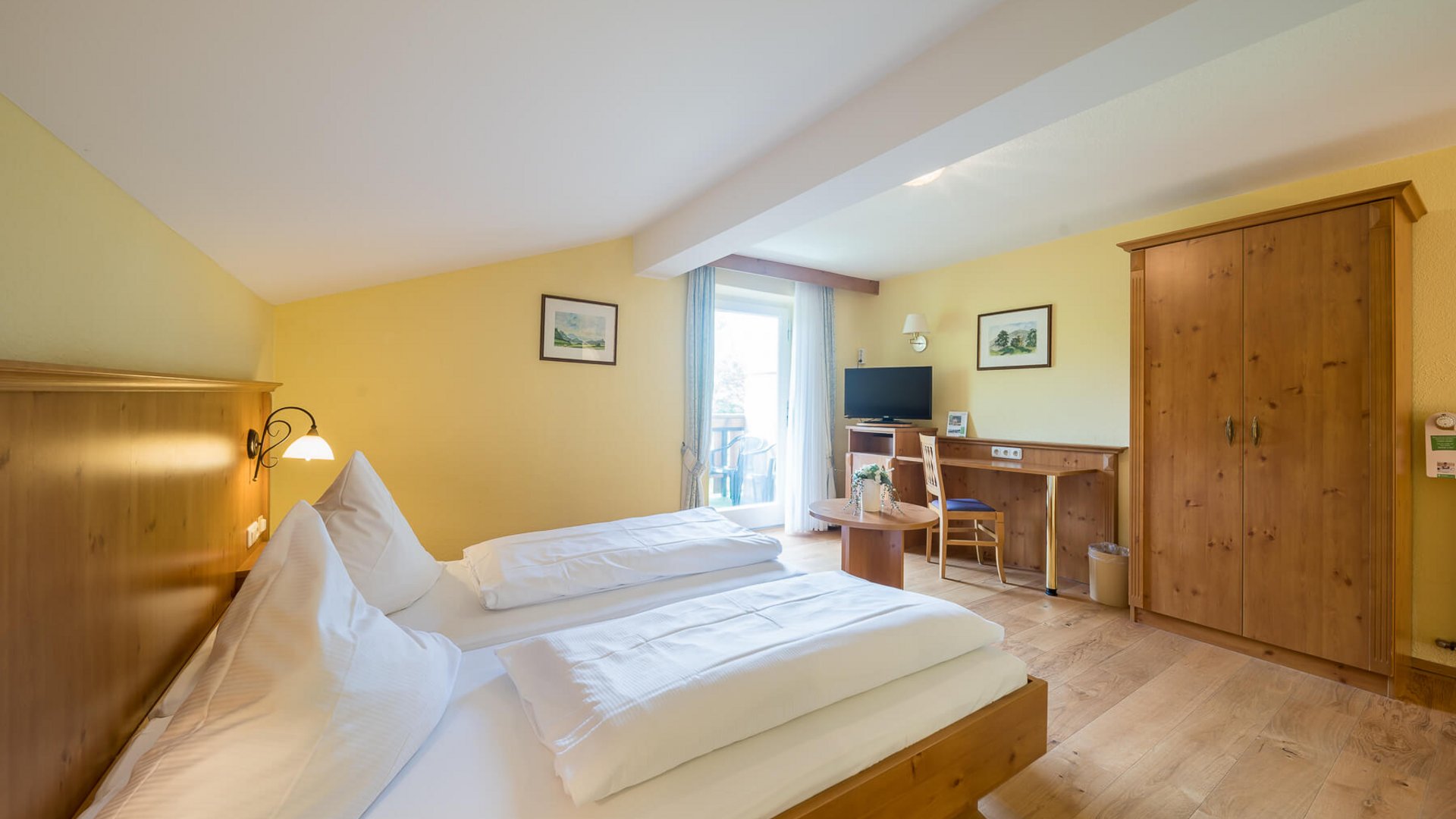 Bright hotel room with double bed, desk, and balcony