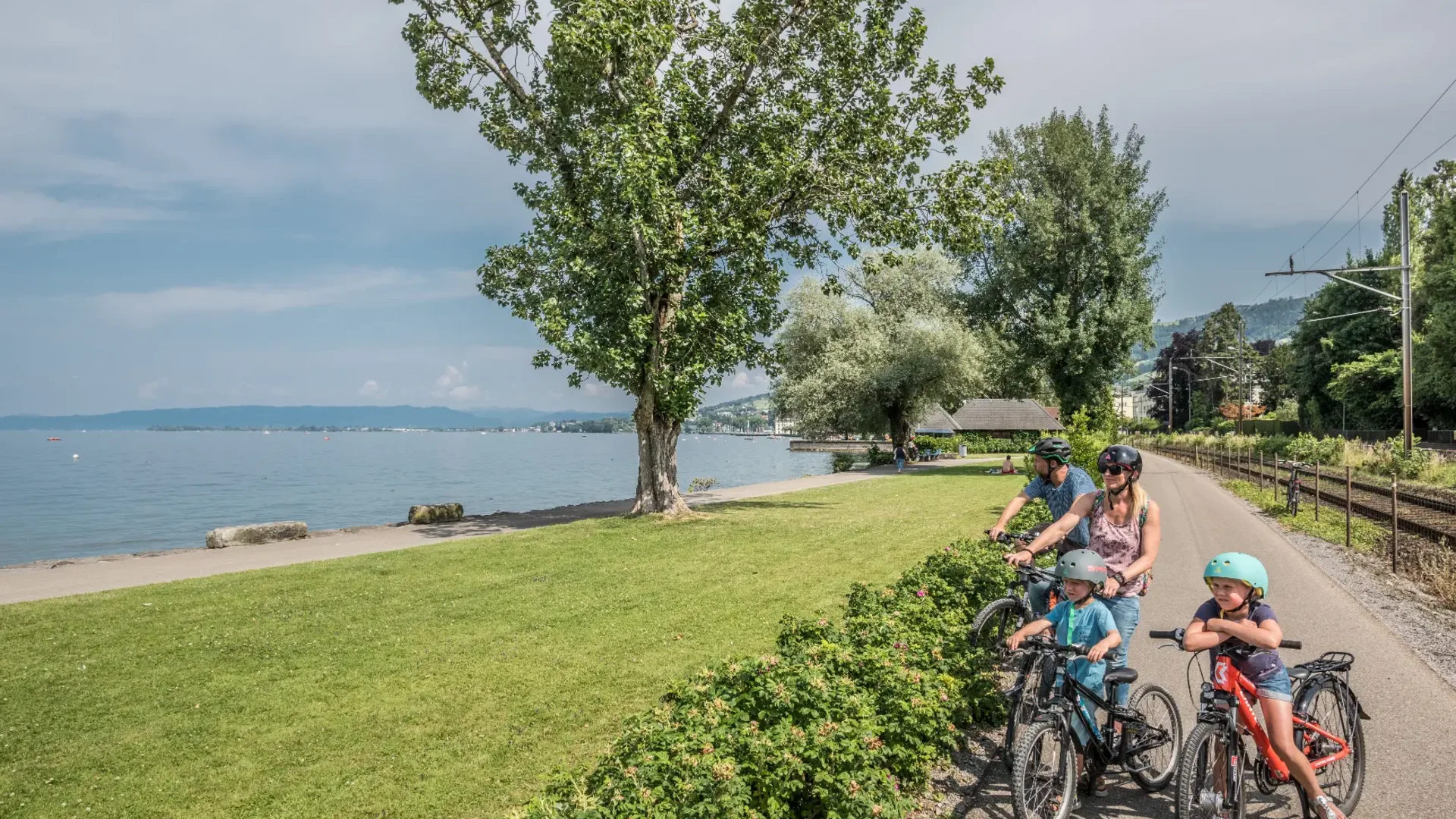 Familie met twee kinderen op fietsen langs een meer op een zonnige dag