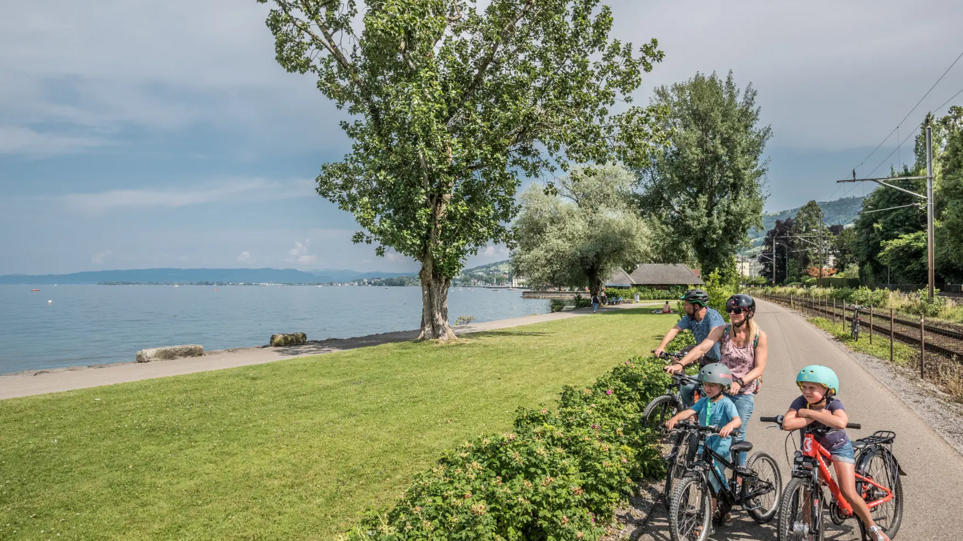 Family with two children on bikes at a lakeside path on a sunny day